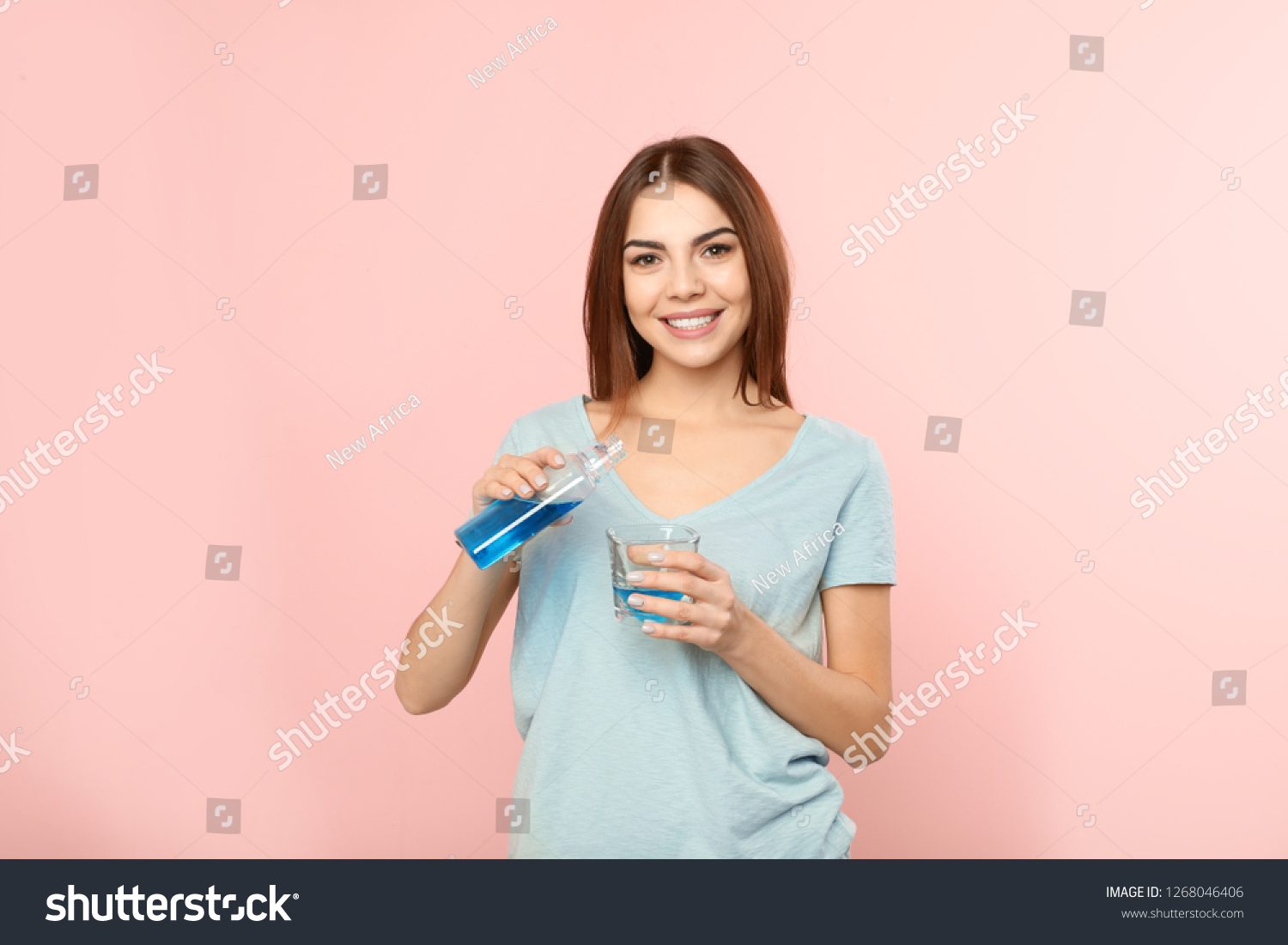 Beautiful woman pouring mouthwash from bottle into glass on color background. Teeth and oral care #1268046406