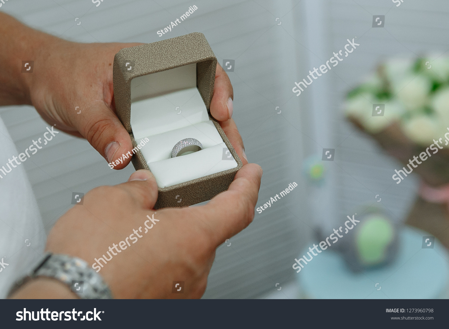 Diamond ring in the hands of a man. On the background of flowers #1273960798
