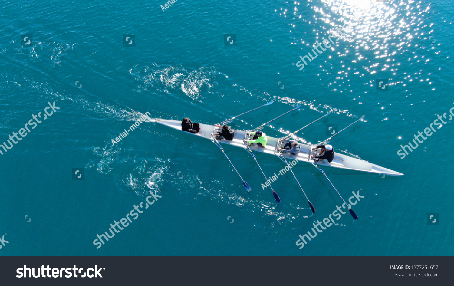 Aerial drone bird's eye view of sport canoe operated by team of young men in emerald clear sea #1277251657