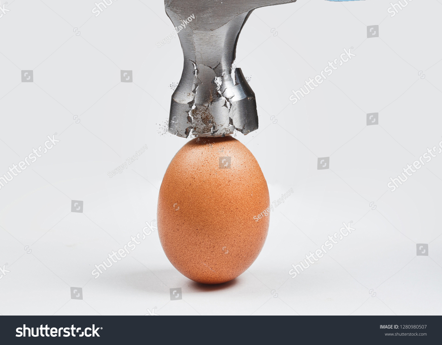 Hammer is breaking chicken egg. Concept of strength, durability, stress resistance and fortitude. #1280980507