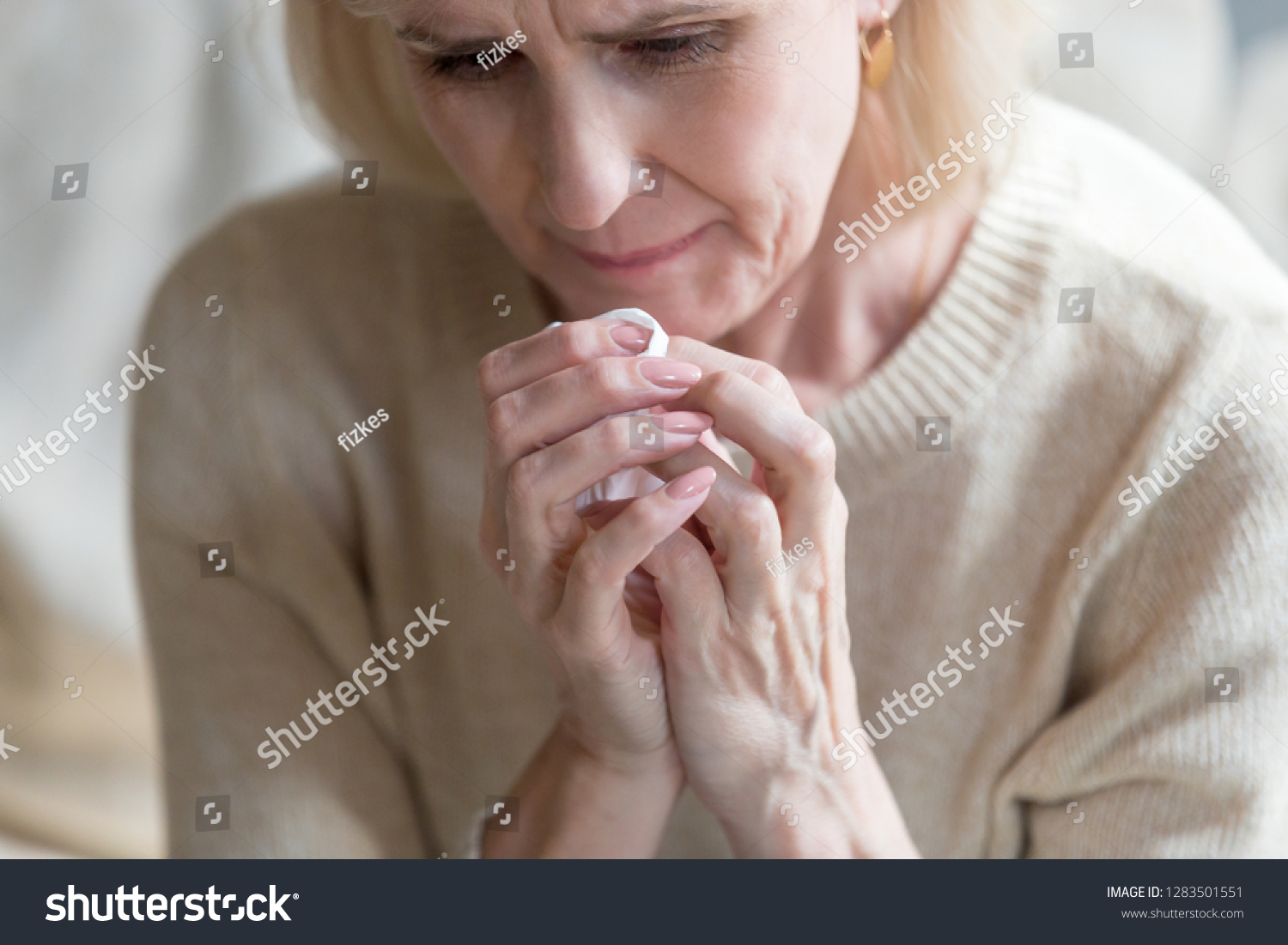 Unhappy middle aged woman folding hands together holding handkerchief crying feels bad and miserable, close up image. Sad life circumstances, death of relative person and terminal illness concept #1283501551