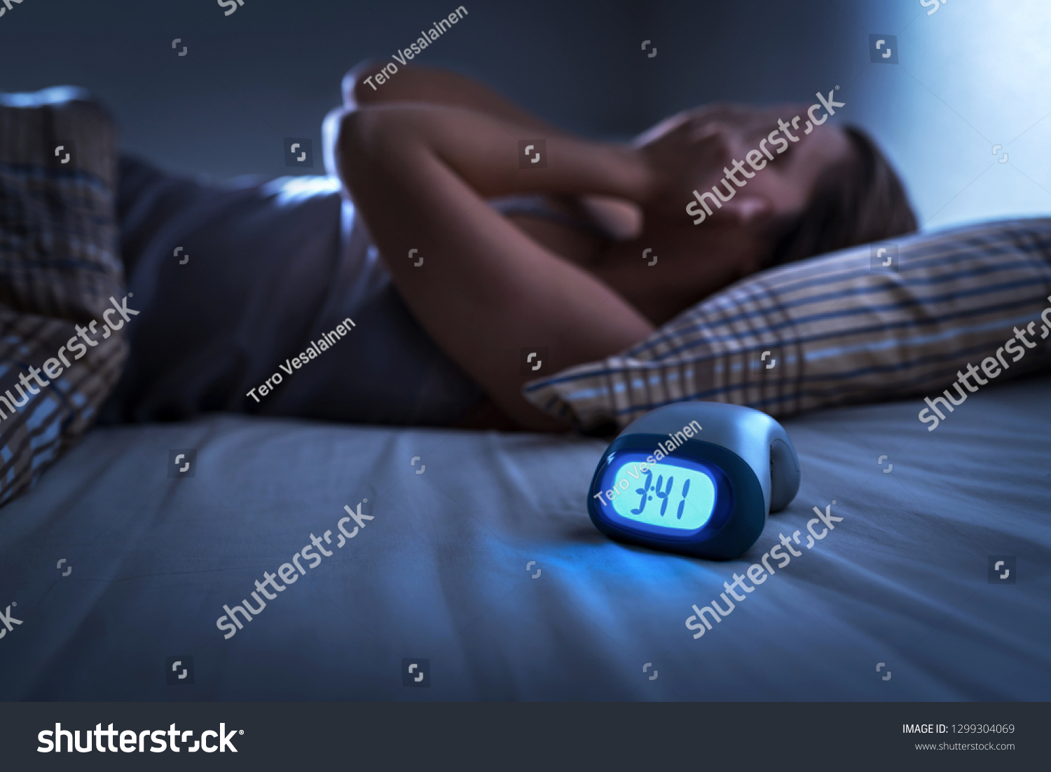Sleepless woman suffering from insomnia, sleep apnea or stress. Tired and exhausted lady. Headache or migraine. Awake in the middle of the night. Frustrated person with problem. Alarm clock with time. #1299304069