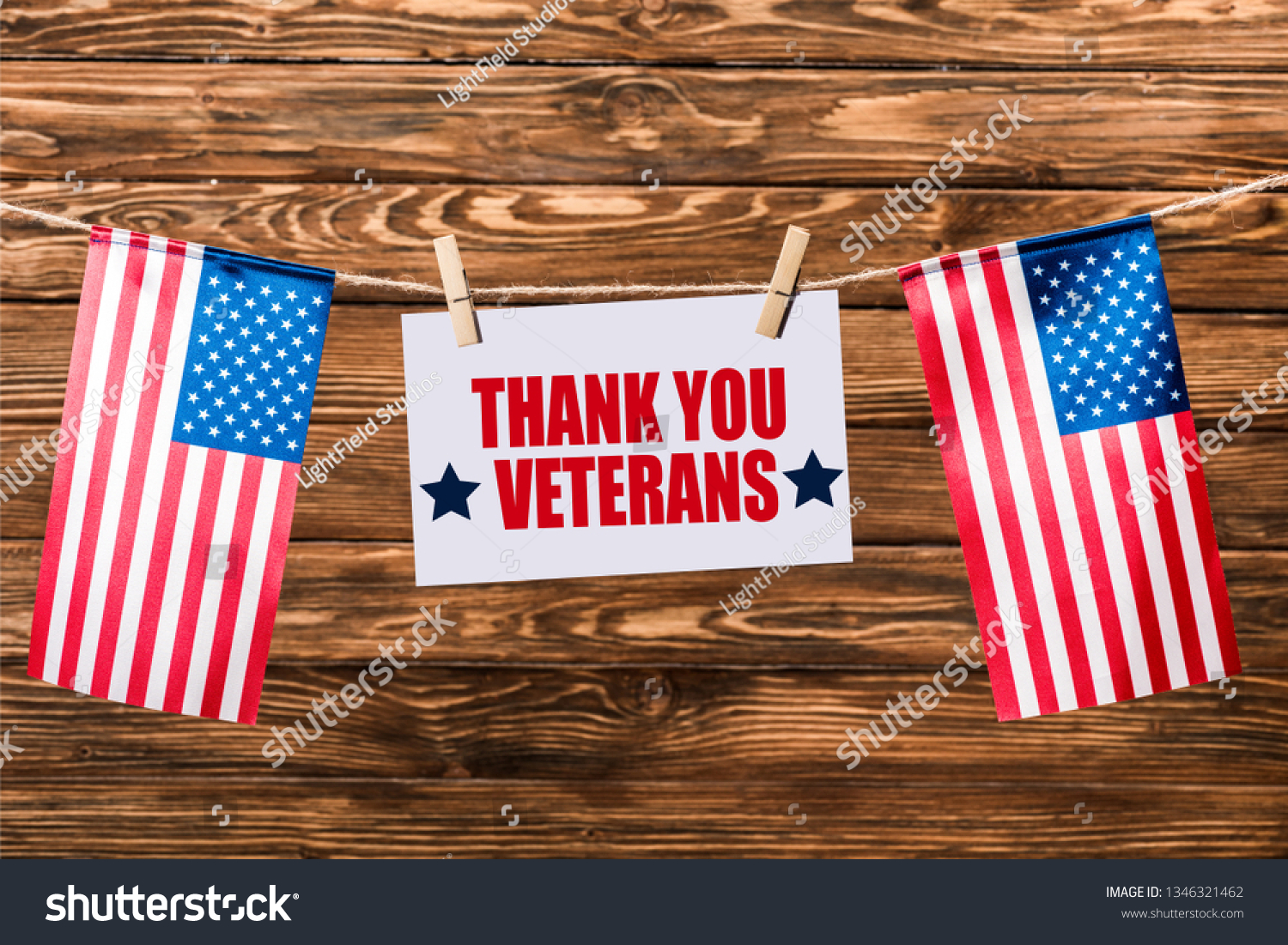 card with thank you veterans lettering hanging on string with pins and american flags on wooden background #1346321462
