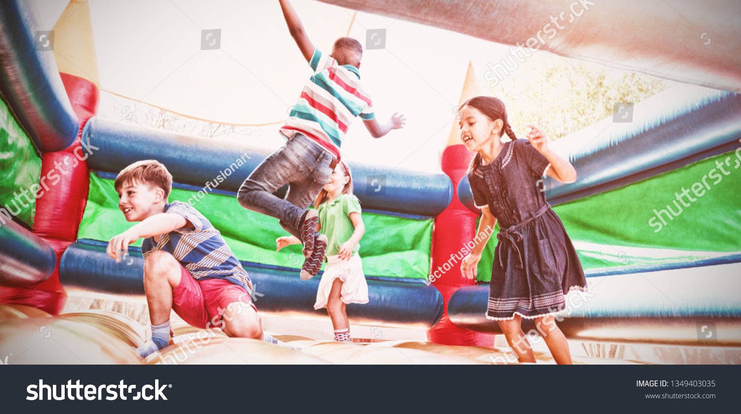Friends jumping on bouncy castle at playground #1349403035