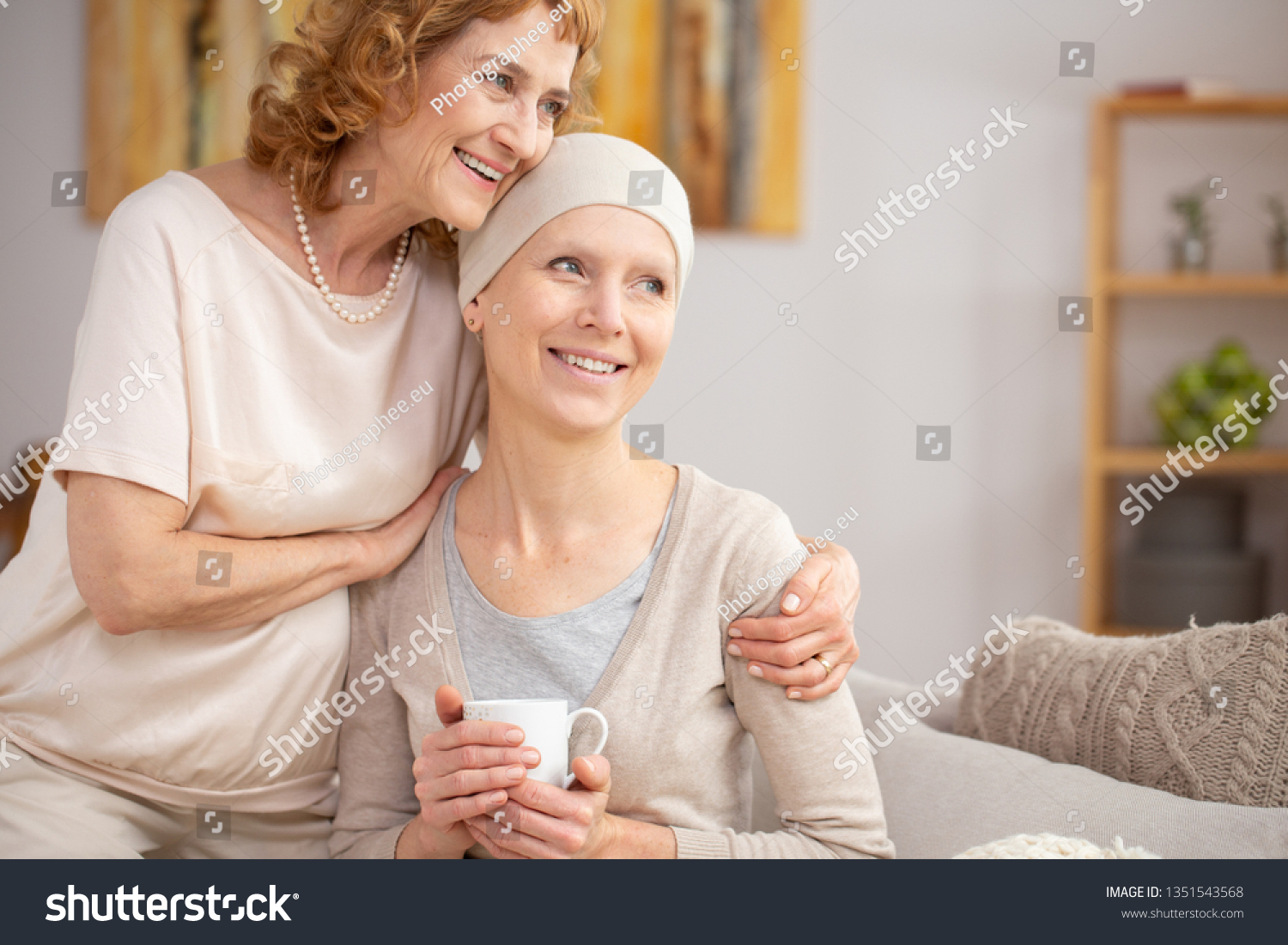 Senior woman suffering from lung cancer sitting at home with her sister enjoining their time after hospital treatment #1351543568