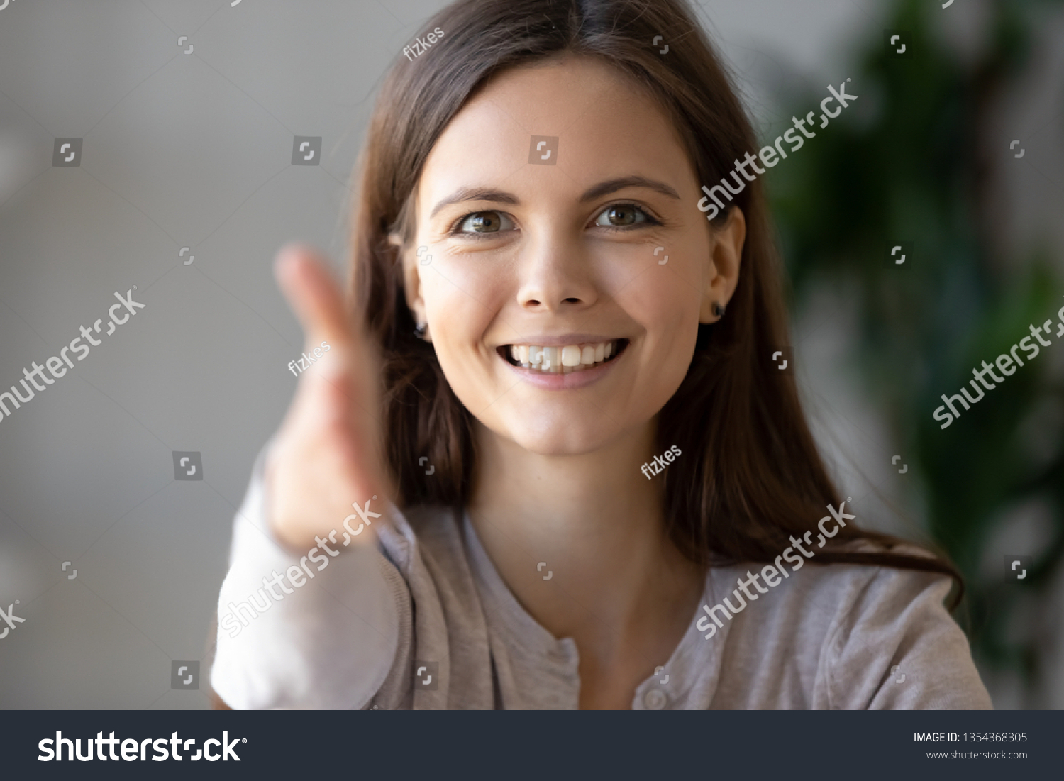 Smiling businesswoman holds out her hand to camera for handshake arm close up, focus on friendly face. Greeting gesture, negotiations, first impressions at acquaintance, hr and congratulations concept #1354368305