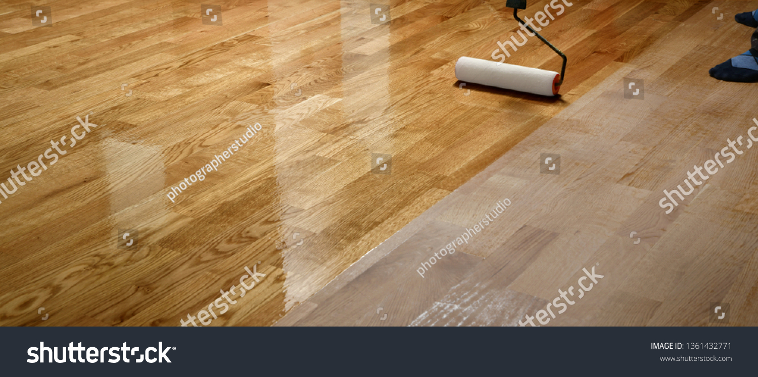 Lacquering wood floors. Worker uses a roller to coating floors. Varnishing lacquering parquet floor by paint roller - second layer. Home renovation parquet #1361432771