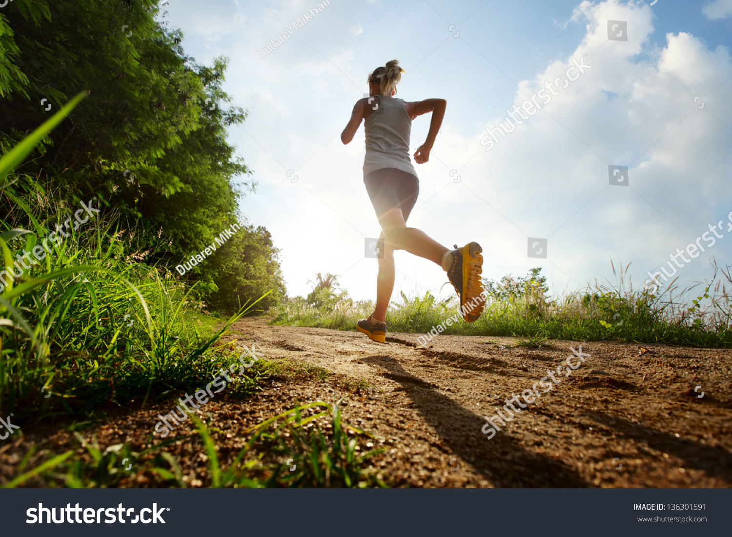Young lady running on a rural road during sunset #136301591