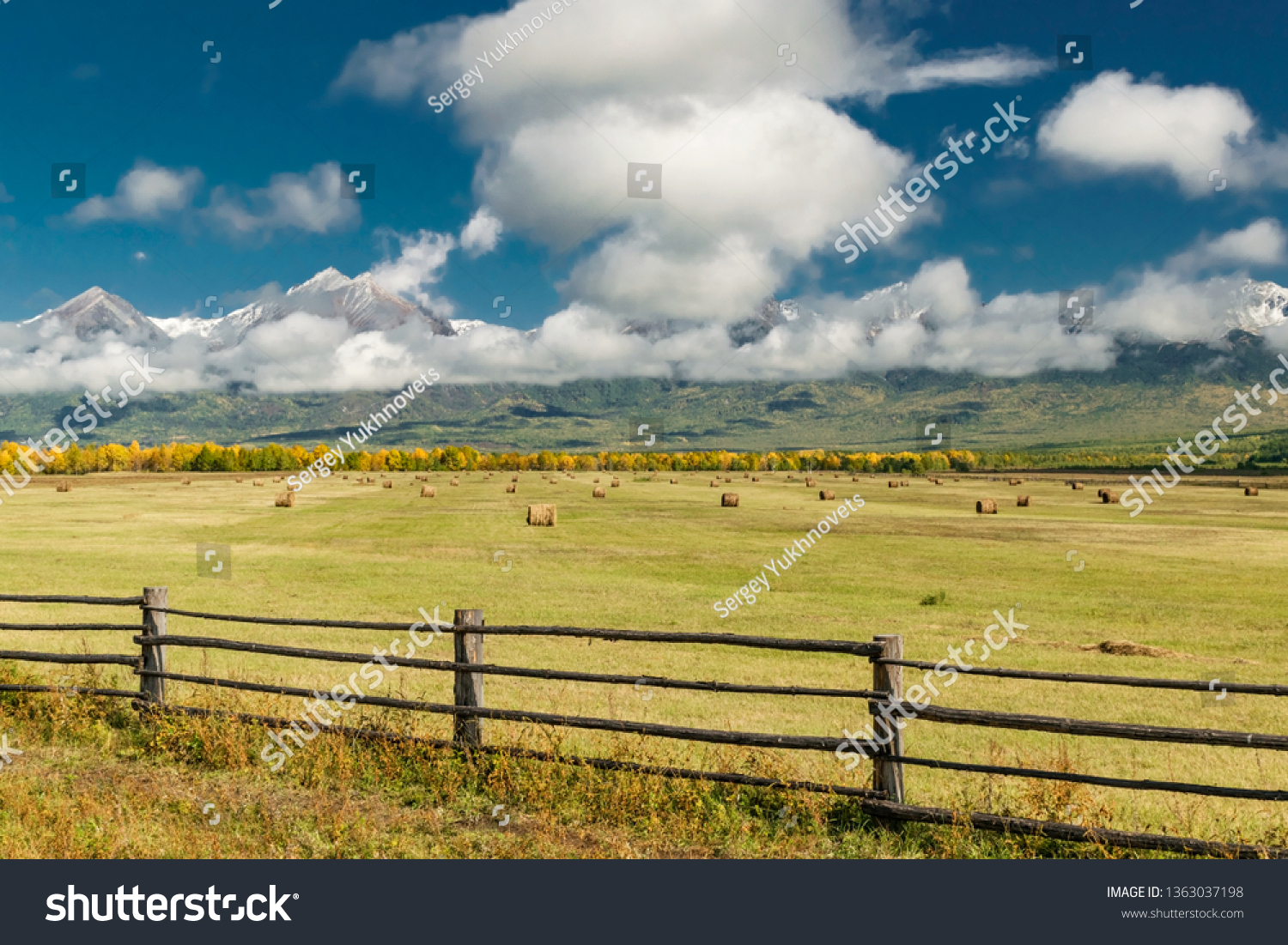 Amazing mountain landscape with cloudy sky, lath fence in the foreground and haystacks, Siberia, Irkutsk region, Russia #1363037198