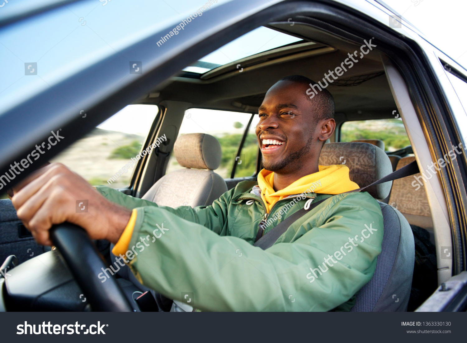 Side portrait of happy african american man driving car #1363330130