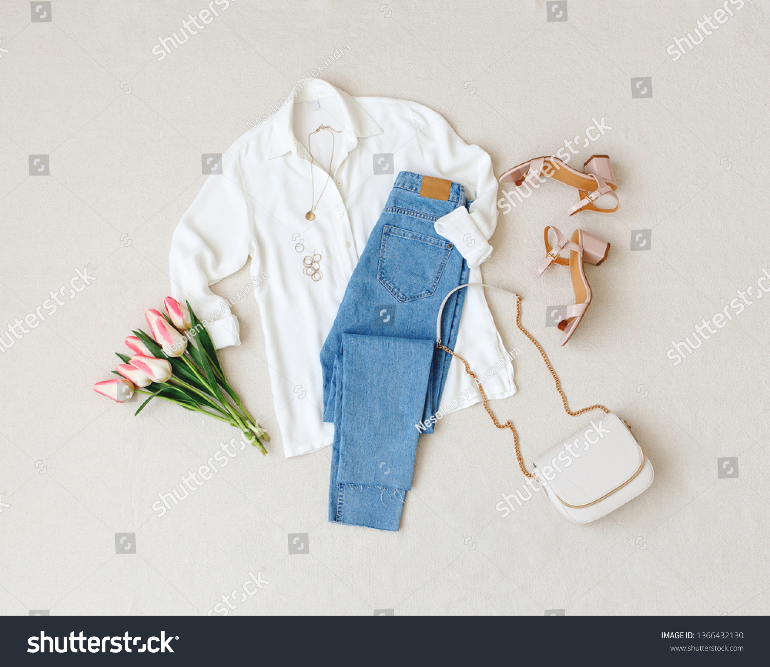 Blue jeans, white shirt, heeled sandals, bag with chain strap, jewelry, bouquet of pink tulips flowers on beige background. Women's stylish spring summer outfit. Trendy clothes. Flat lay, top view. #1366432130