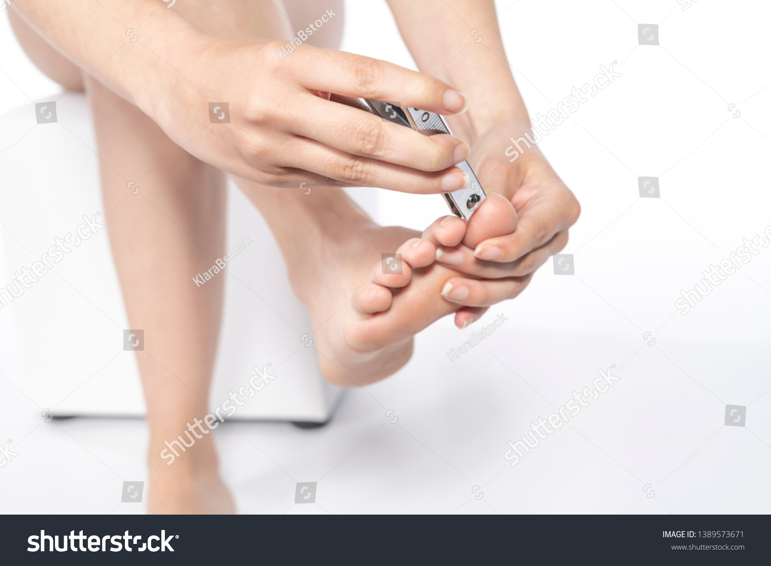 Woman clipping her toenails. isolated on white background. #1389573671