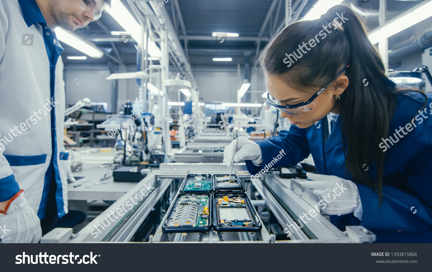 Shot of an Electronics Factory Workers Assembling Circuit Boards by Hand While it Stands on the Assembly Line. High Tech Factory Facility. #1393815866