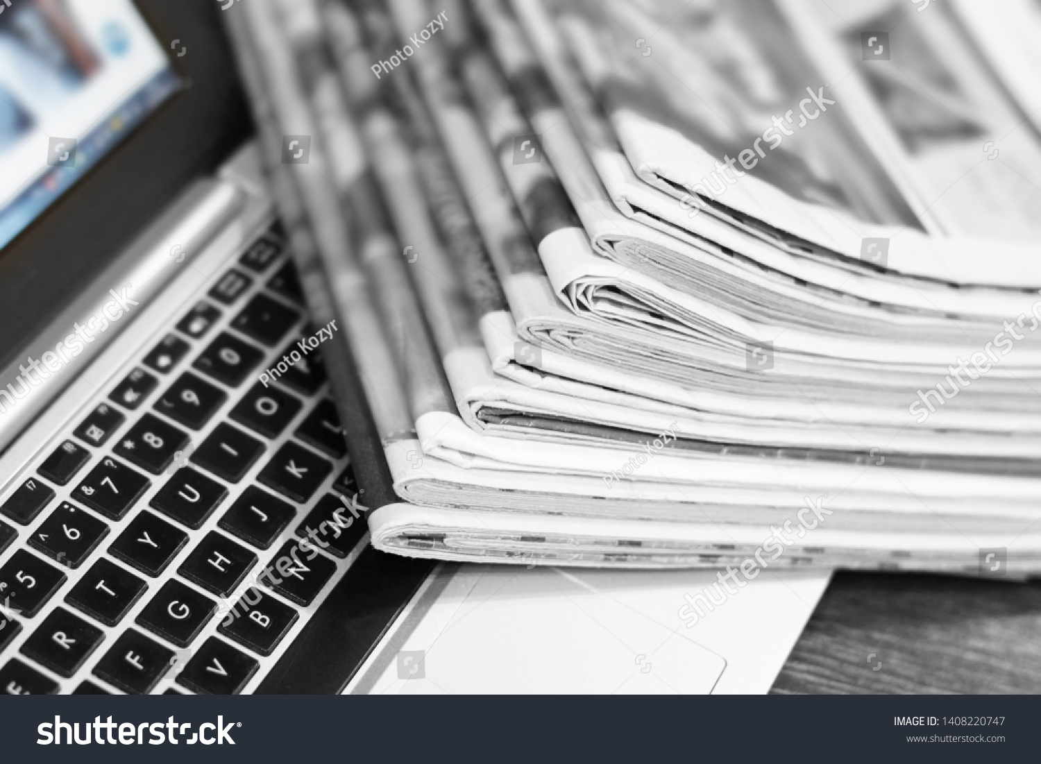 Newspapers and laptop. Pile of daily papers with news on the computer. Pages with headlines, articles folded and stacked on keypad of electronic device. Modern gadget and old journals, focus on paper  #1408220747