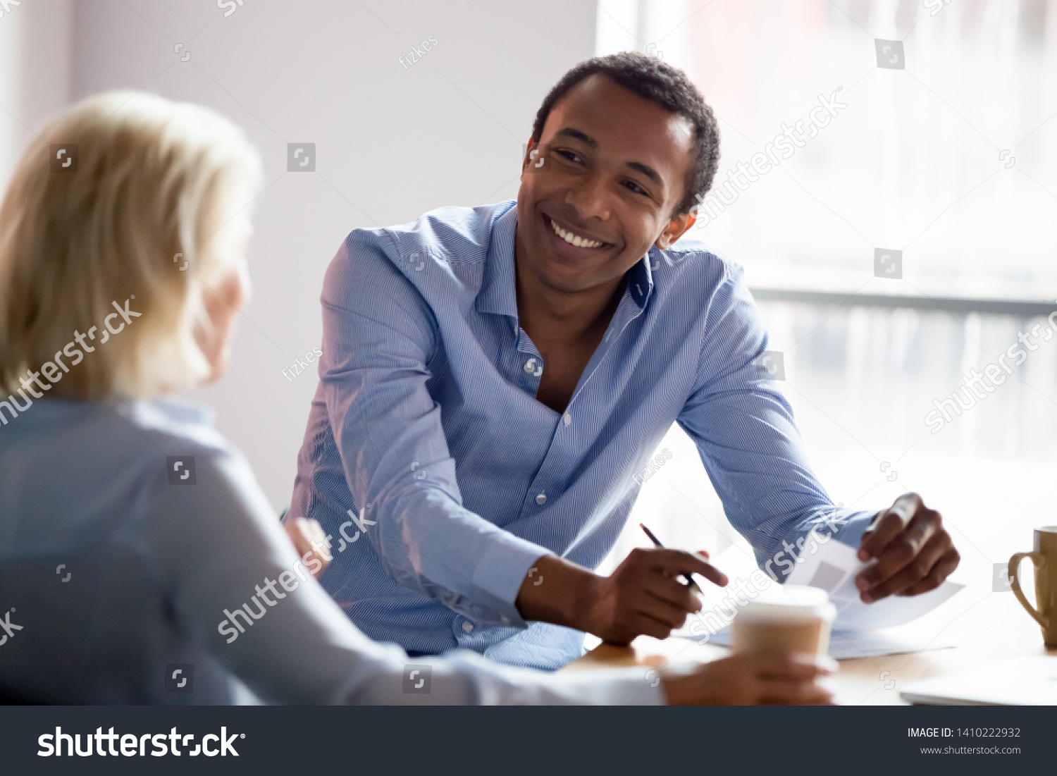 Smiling african american professional manager advisor designer talking with client listen to customer preferences at business meeting, diverse colleagues having conversation share design idea at work #1410222932