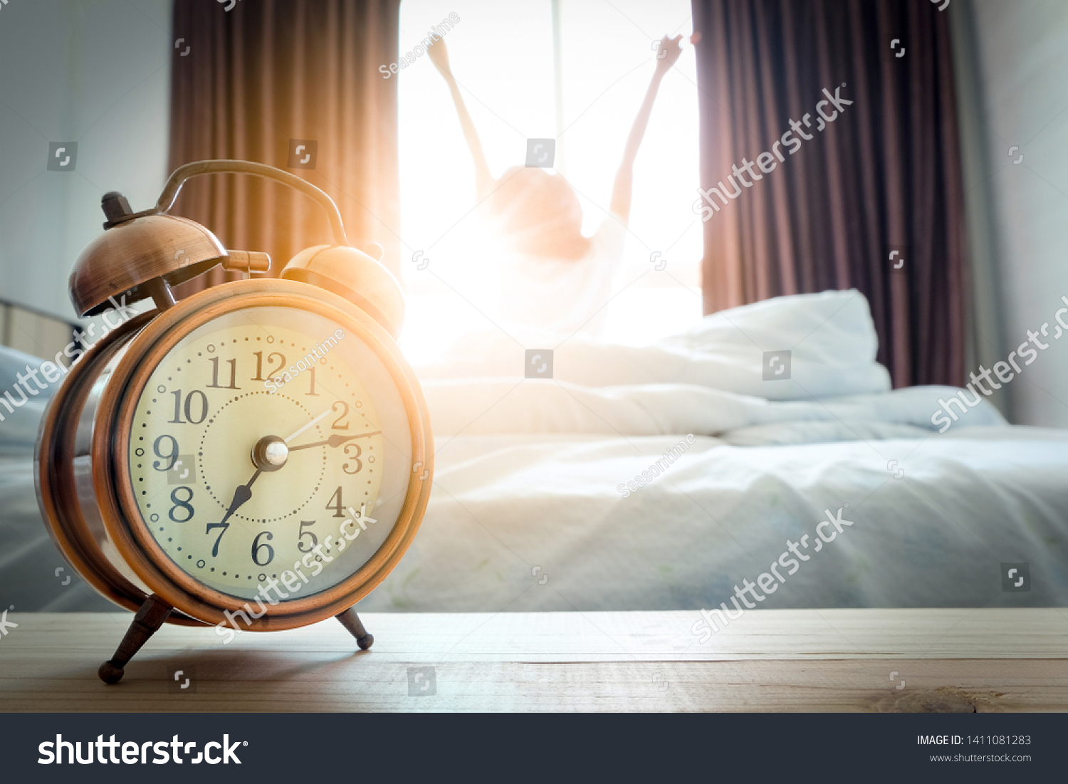 Morning of a new day, alarm clock wake up woman sitting in the room. A woman stretch the muscles at window. Health and care concepts #1411081283