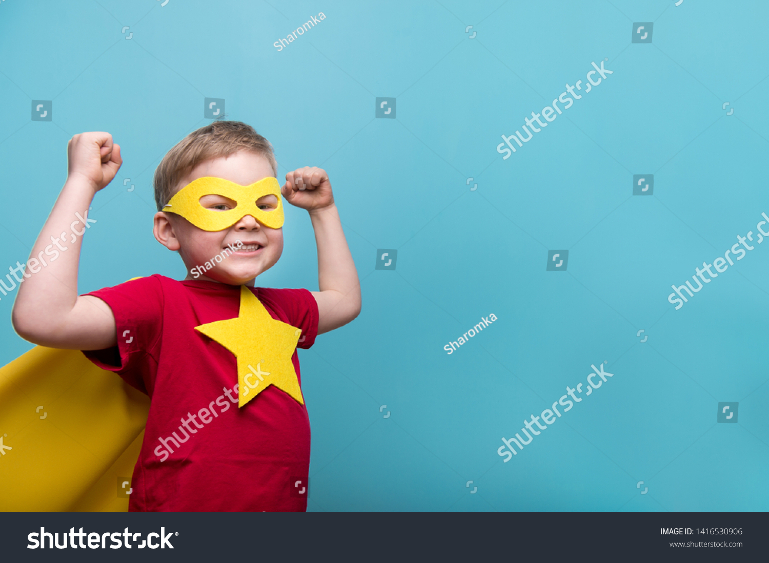 Little child superhero with yellow cloak and star. Happy smiling kid in glasses ready for education. Success, motivation concept. Back to school. Little businessman isolated on blue, Boy superhero.  #1416530906