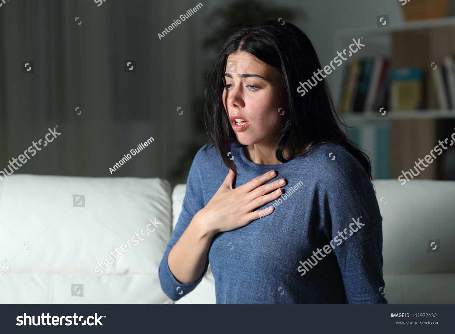 Woman suffering an anxiety attack alone in the night on a couch at home #1419724301