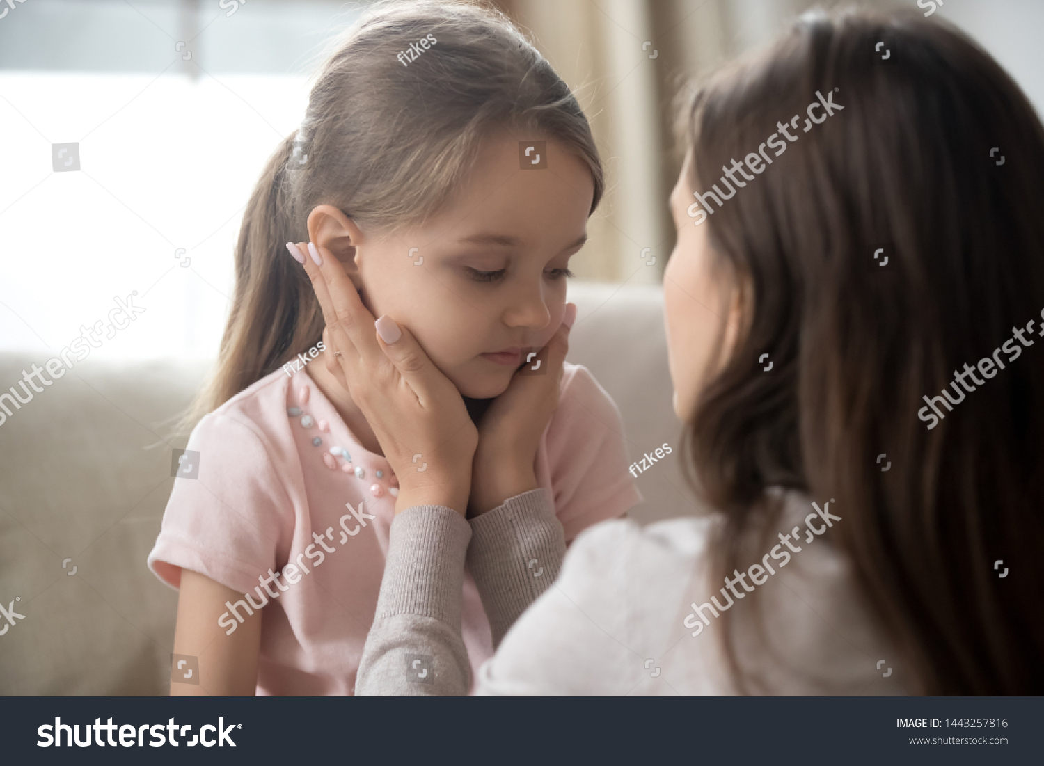 Loving young mother touching upset little daughter face, expressing support, young mum comforting offended adorable preschool girl, showing love and care, child psychologist concept, close up #1443257816