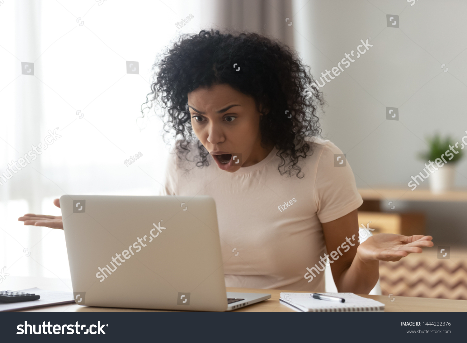 Shocked angry stressed african black woman customer looking at laptop screen feel bad surprise annoyed reading online news frustrated with stuck computer problem website error sit at home office desk #1444222376