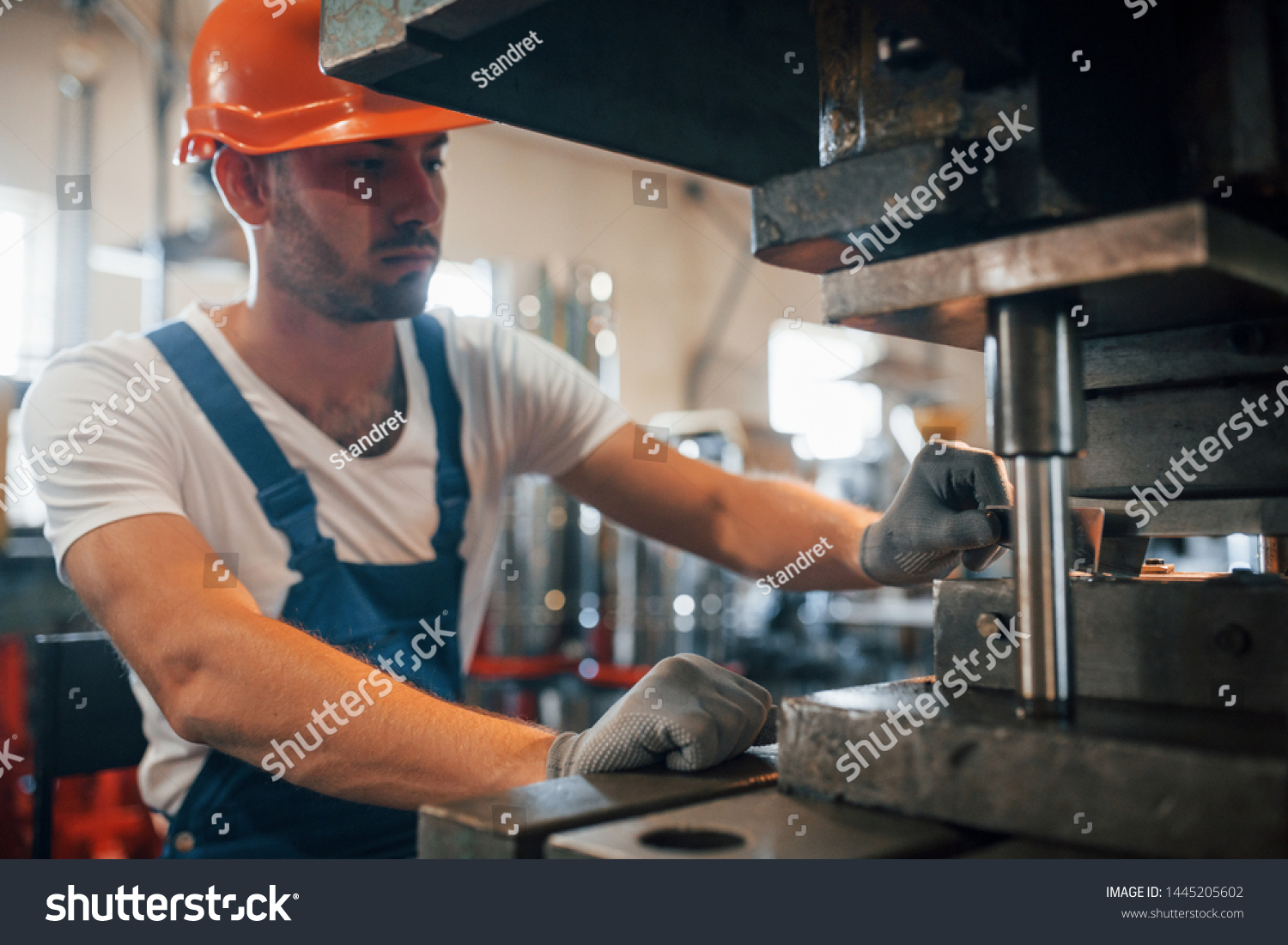 Holds slice of metal. Man in uniform works on the production. Industrial modern technology. #1445205602