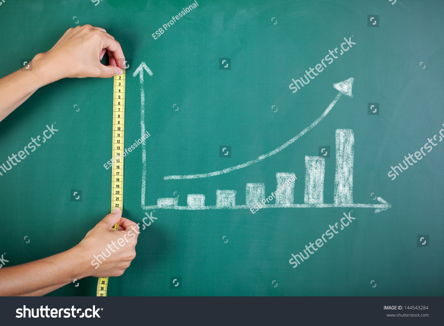 Closeup of woman's hands measuring bar graph with tape on blackboard #144543284
