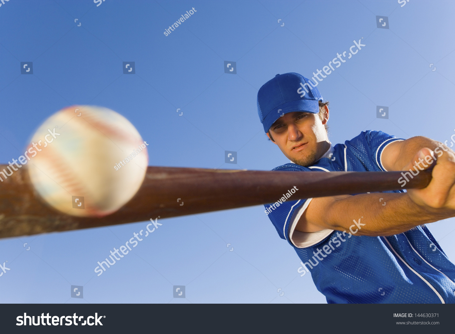 Baseball player hitting the ball with a bat against clear blue sky #144630371