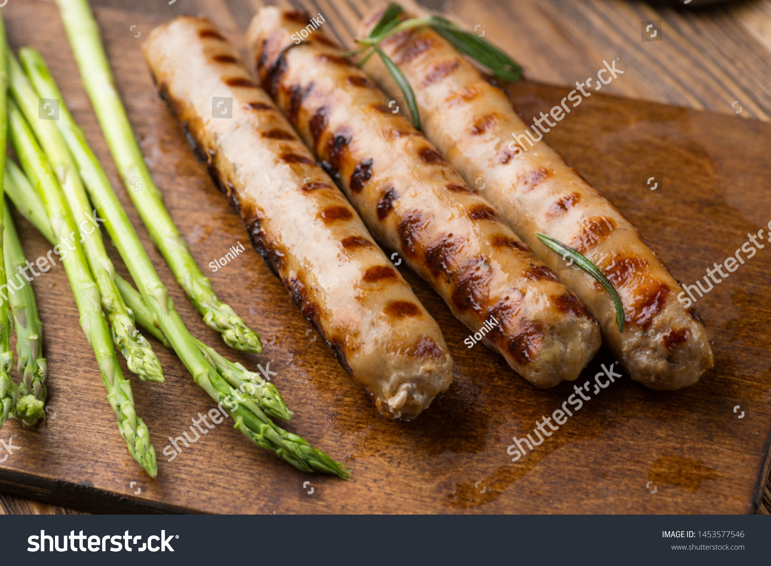 Fried sausages with asparagus.  on a wooden serving Board. Great beer snack on a dark background. Top view with copy space #1453577546
