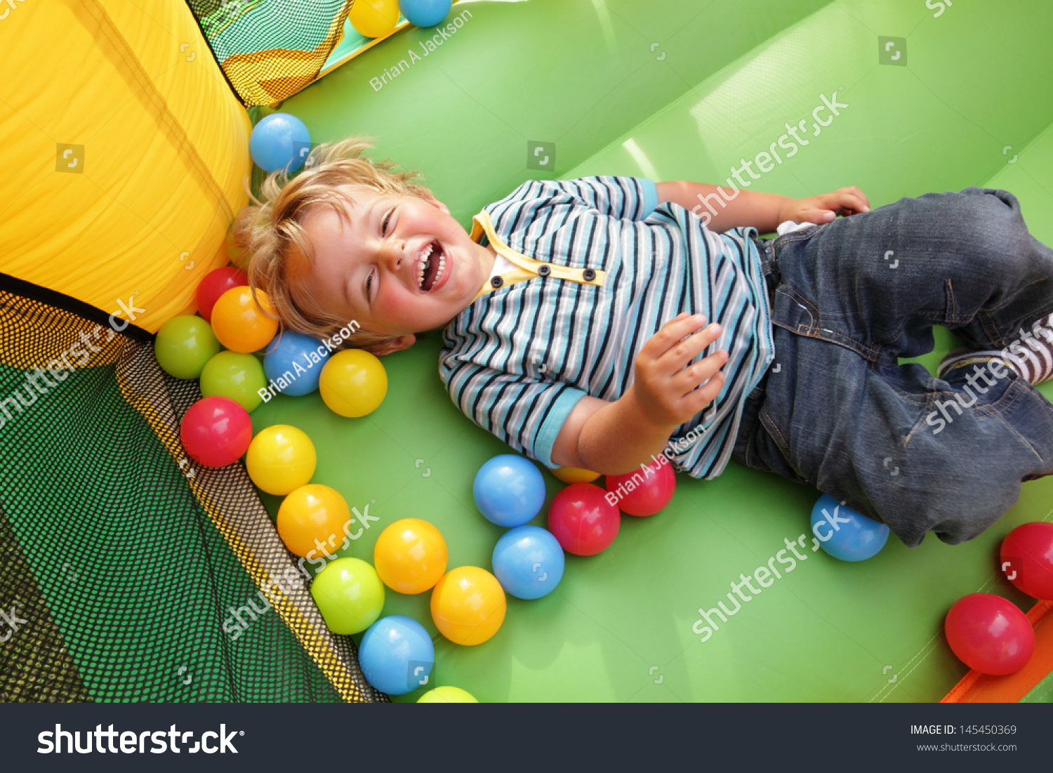 2 year old boy smiling on an inflatable bouncy castle #145450369