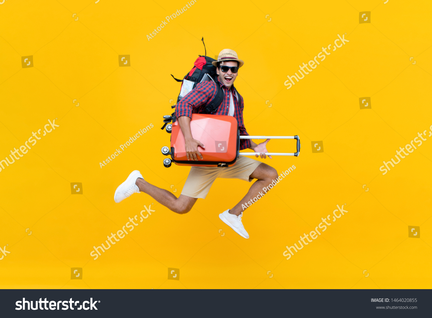 Excited happy young Asian man tourist with luggage jumping isolated on yellow studio background #1464020855