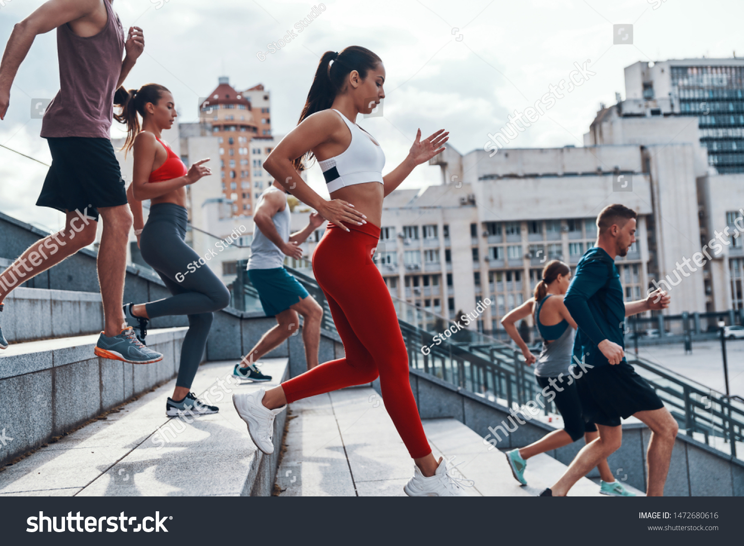 Group of young people in sports clothing jogging while exercising on the stairs outdoors                     #1472680616