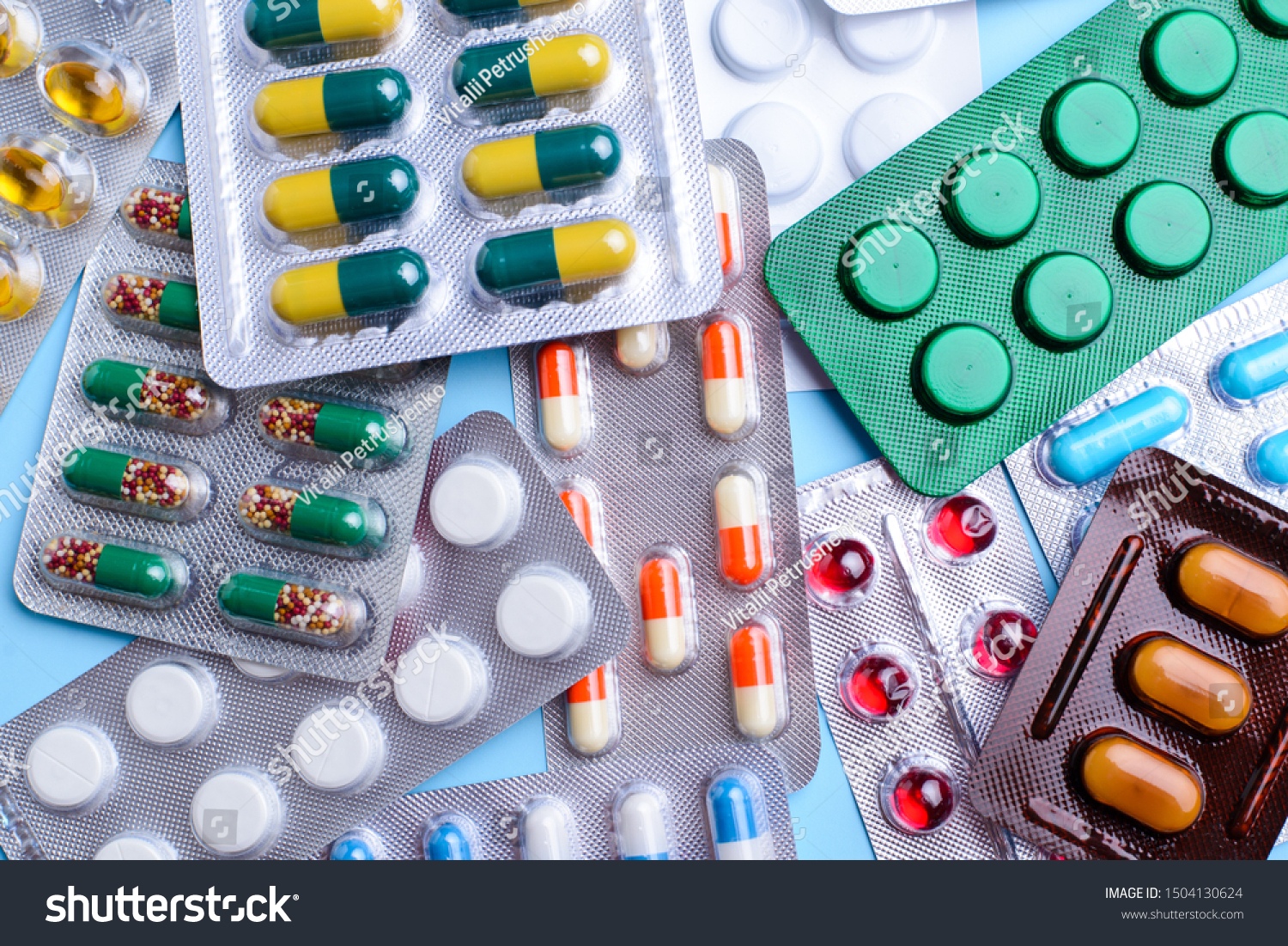 Different tablets, pills in foil blister packs, medications drugs on blue background #1504130624
