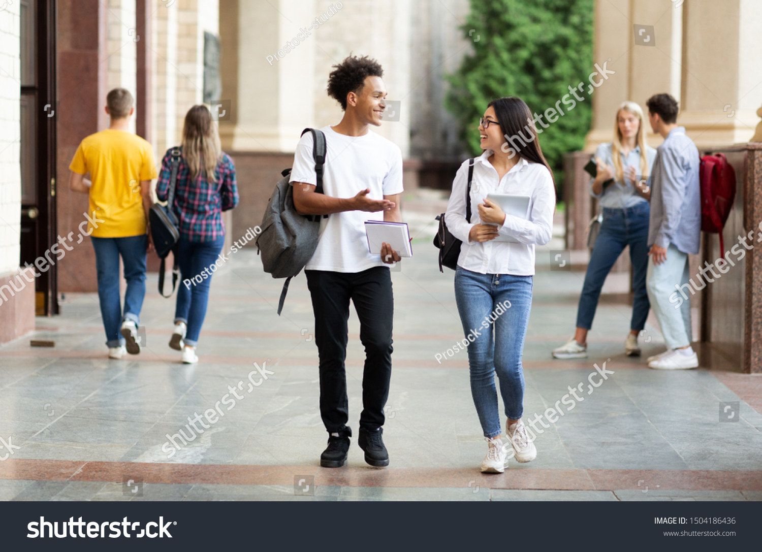 Diverse classmates chatting, walking after classes in university campus outdoors #1504186436
