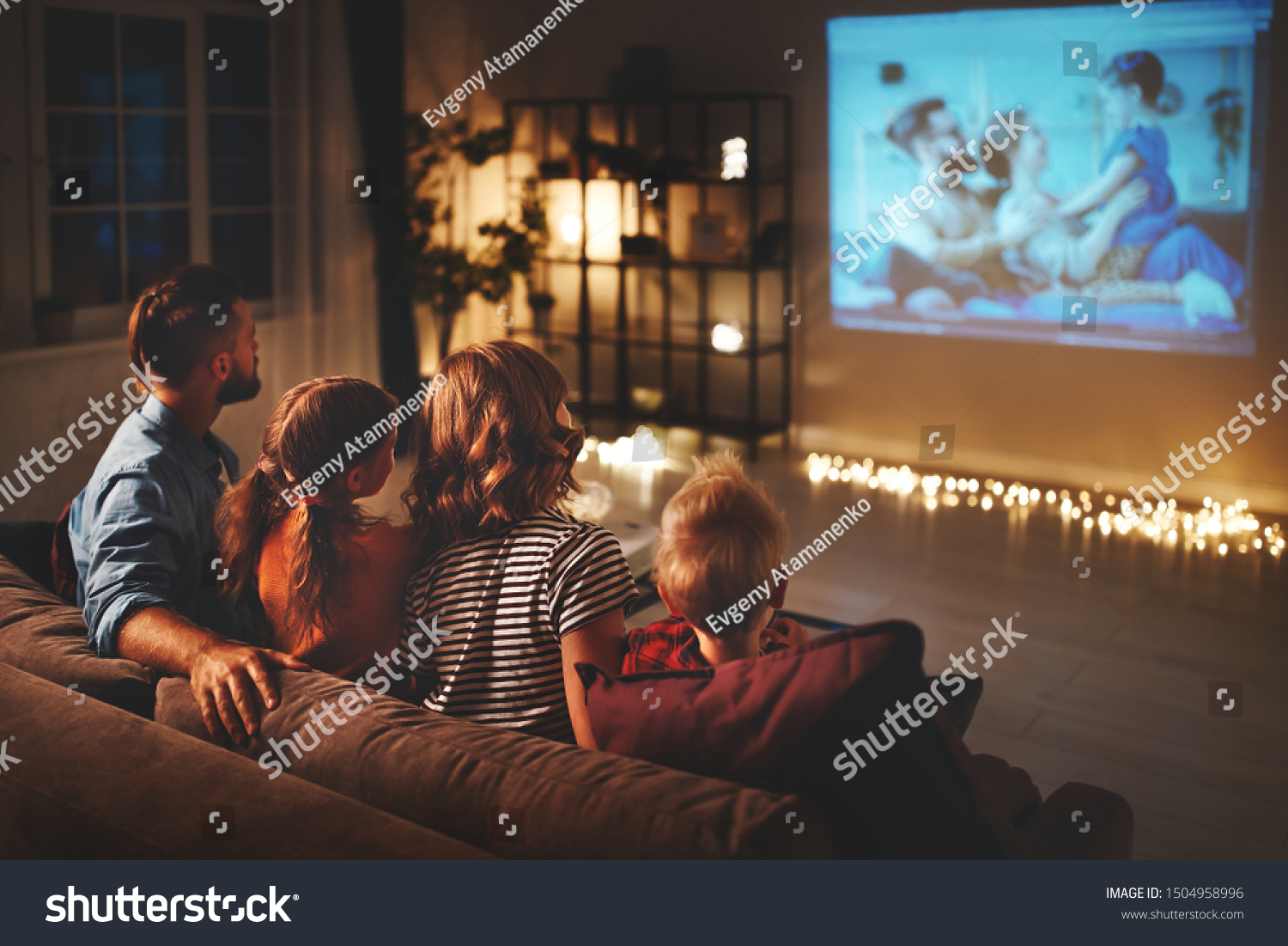 family mother father and children watching projector, TV, movies with popcorn in the evening   at home  #1504958996