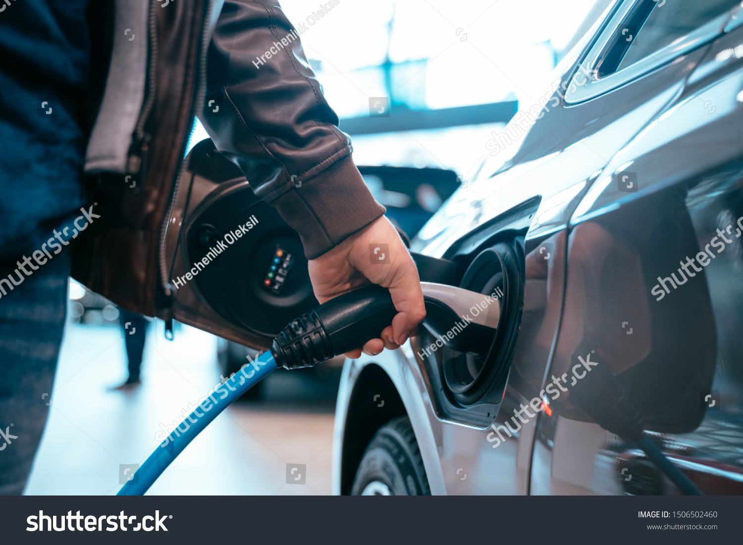 Human hand is holding Electric Car Charging connect to Electric car #1506502460