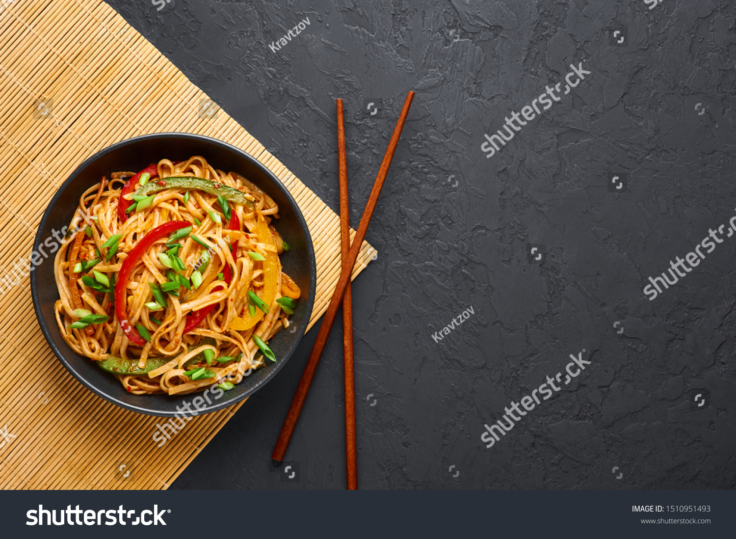 Vegetarian Schezwan Noodles or Vegetable Hakka Noodles or Chow Mein in black bowl at dark background. Indo-chinese cuisine hot dish with udon noodles, vegetables and chilli sauce. Copy space #1510951493
