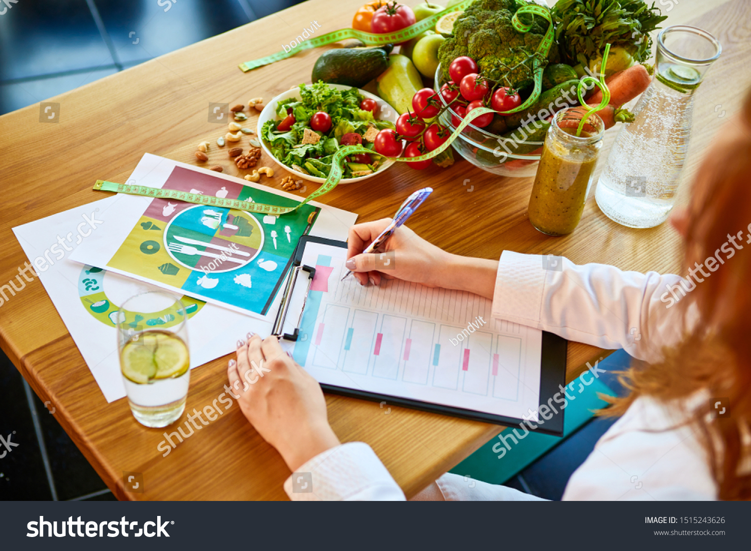 Woman dietitian in medical uniform with tape measure working on a diet plan sitting with different healthy food ingredients in the green office on background. Weight loss and right nutrition concept #1515243626