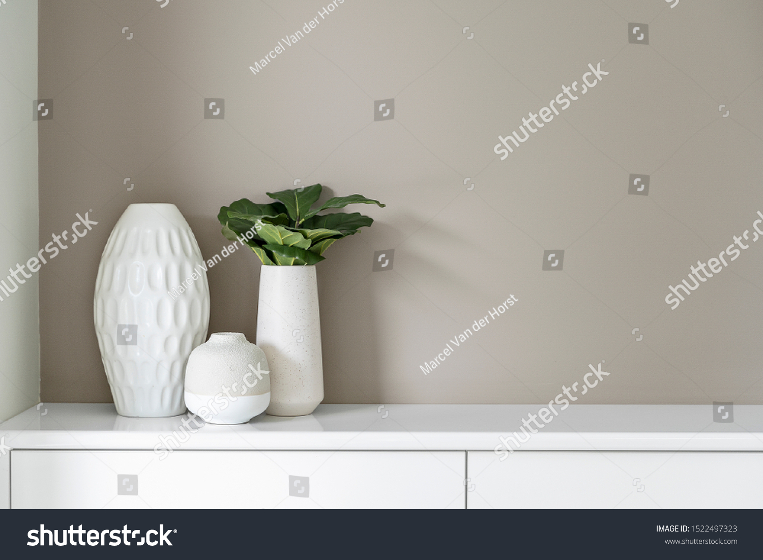 grey and white vases atop a white benchtop cabinet with one green plant in it colored white and grey #1522497323