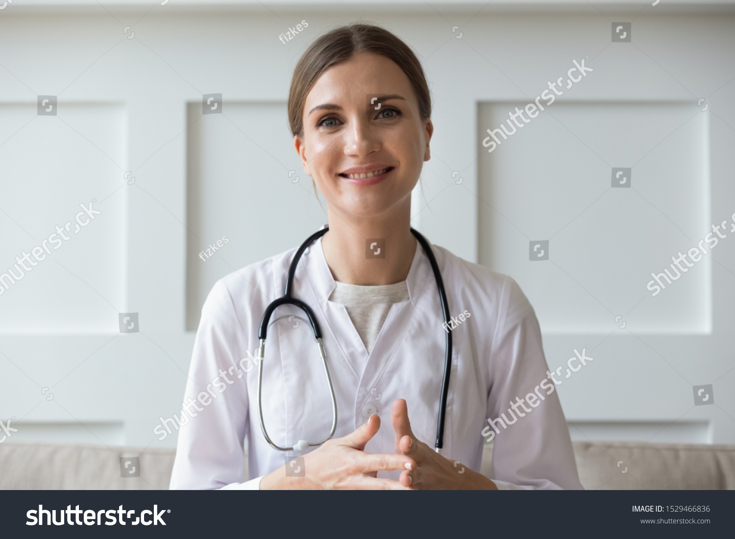 Head shot of woman wearing white coat stethoscope on shoulders looking at camera, doctor make video call interact through internet talk with patient provide help online counseling and therapy concept #1529466836