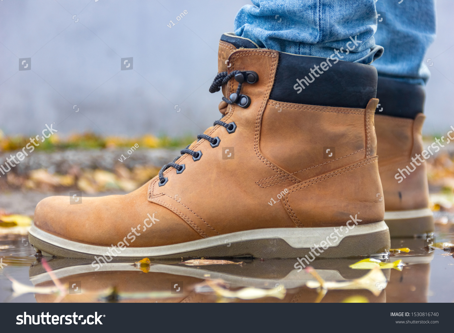 Beautiful leather beige men's high spring-autumn boots. Stylish and fashion casual shoes in autumn weather in the puddle water close-up #1530816740