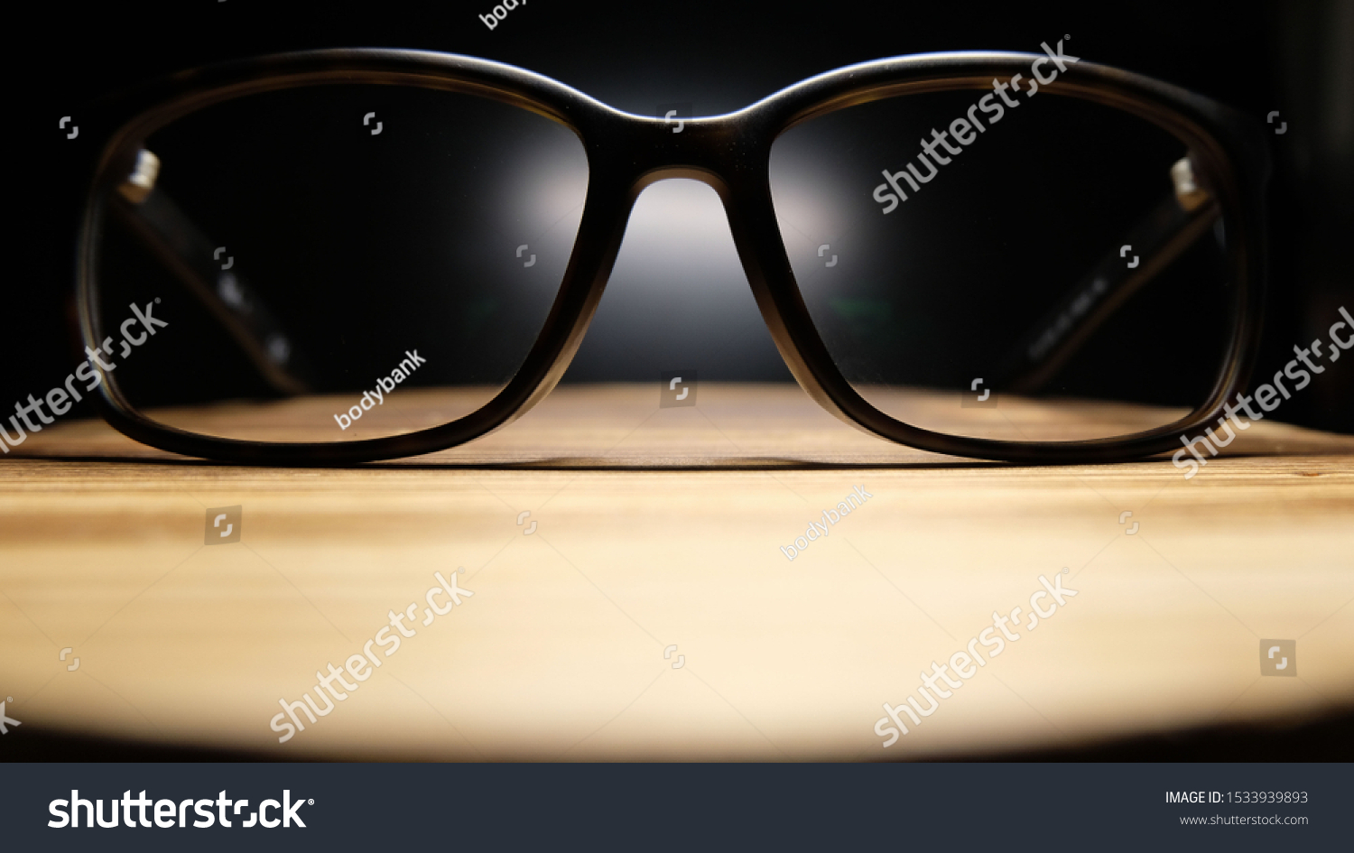 The glasses have black legs that shine through the eyepiece points on the wooden table. On a black background #1533939893