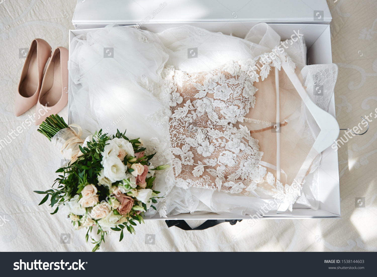 Luxury wedding dress in white box, beige women's shoes and bridal bouquet on bed, copy space. Bridal morning preparations. Wedding concept #1538144603