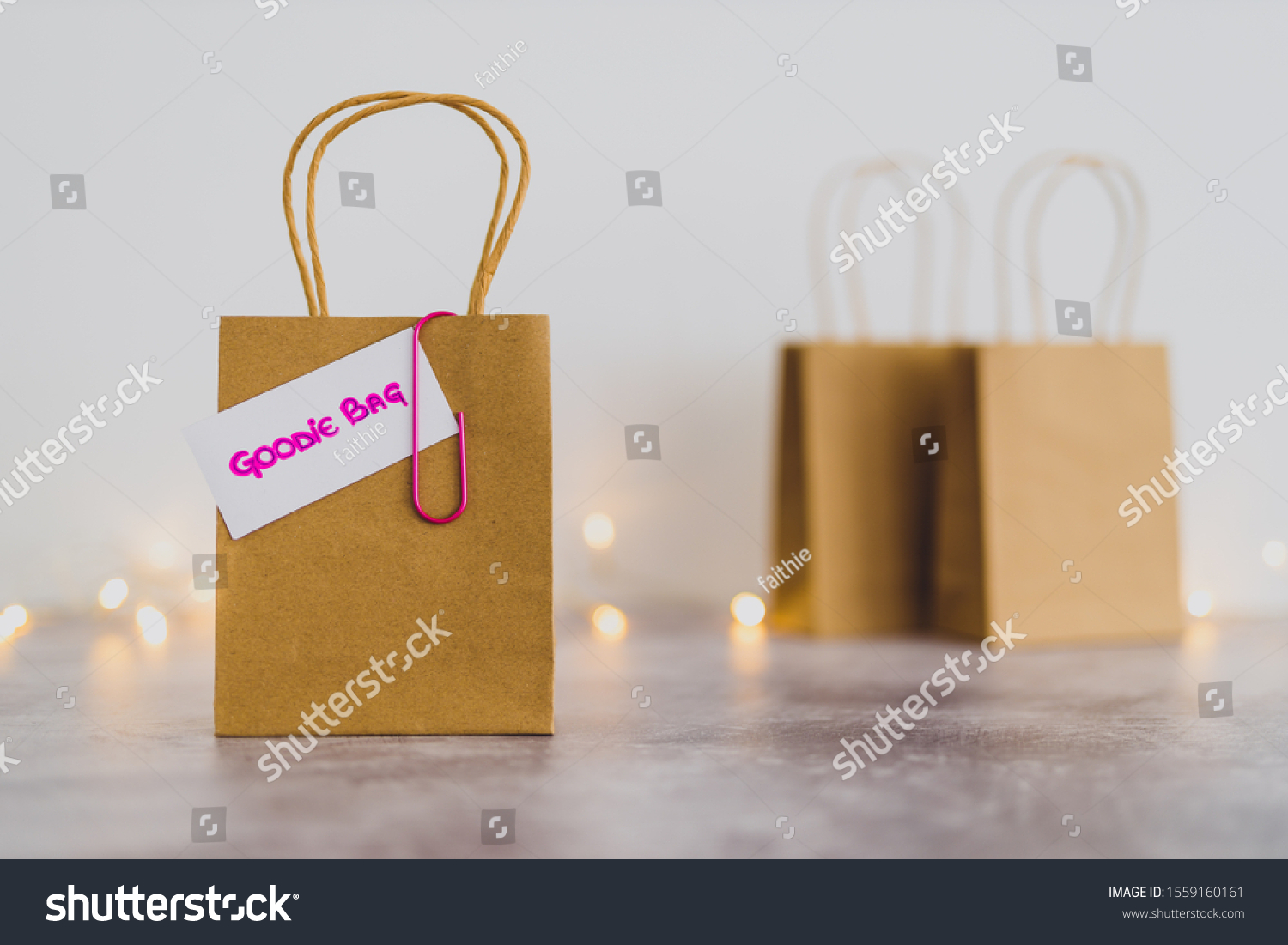 free samples and gifting conceptual still-life, shopping bag with price tag with Goodie Bag text on it and other bags in the background shot at shallow depth of field with bokeh and fairy lights #1559160161