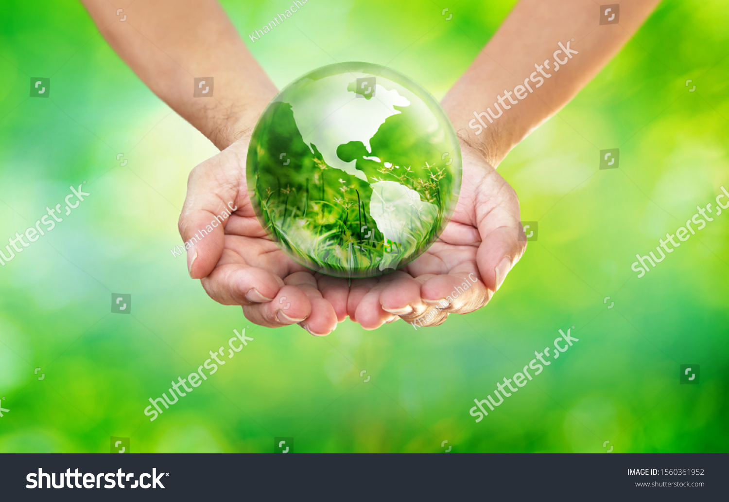 Hands holding globe glass earth with green grass field in side on blurred light nature background,  World Environment Day and Creating the Green Clean World with Your Own Way Concept #1560361952