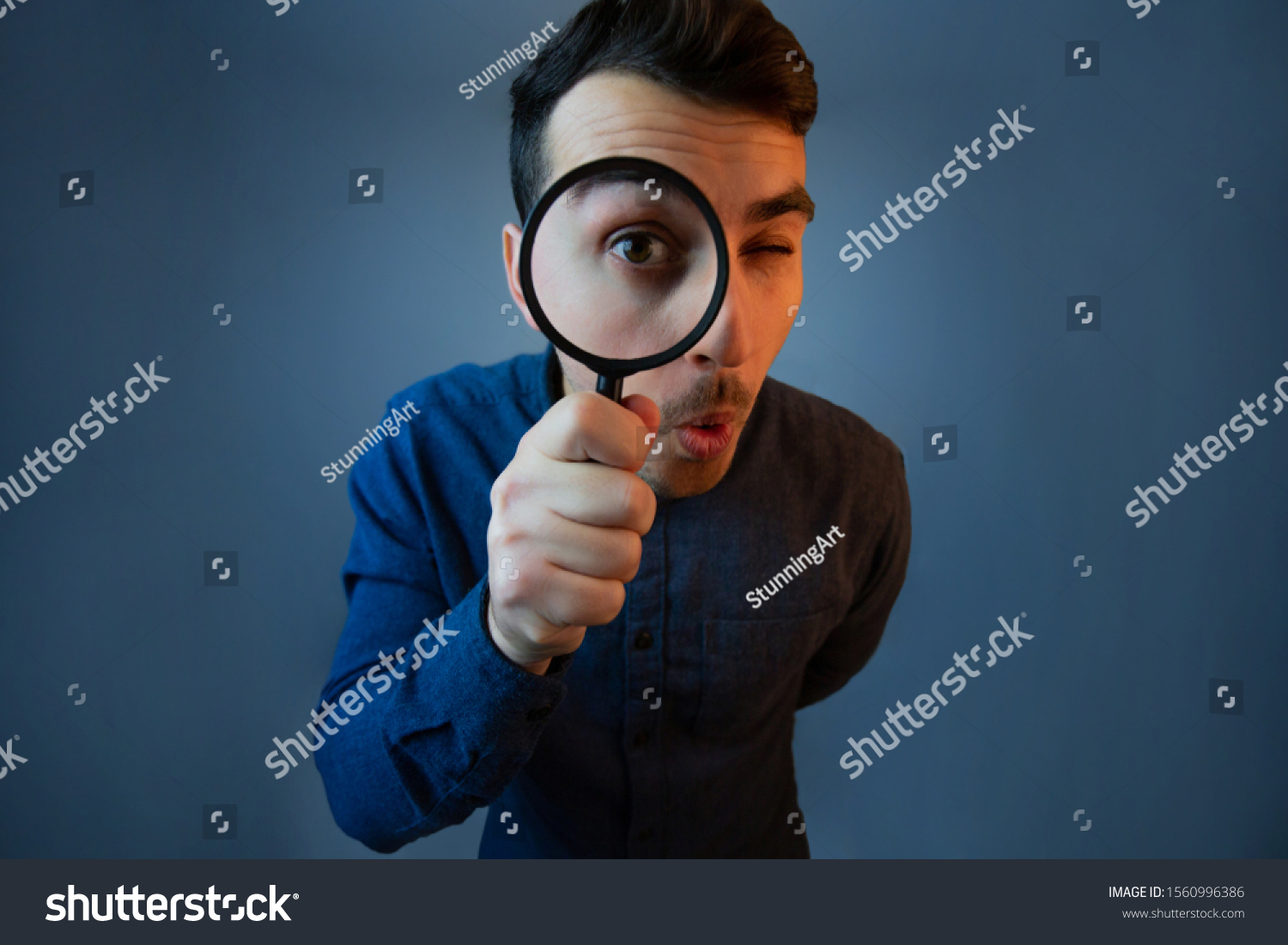 Curious young man with magnifying glass Isolated on grey background. Surprised Young man student holding magnifying glass. #1560996386