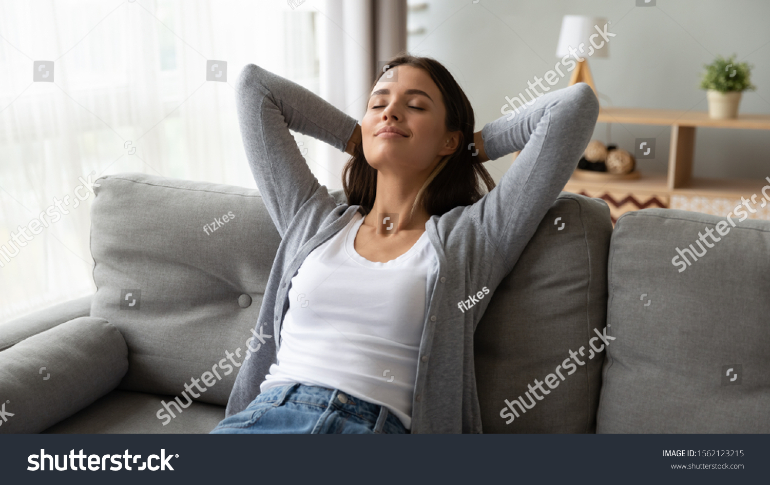 Relaxed serene pretty young woman feel fatigue lounge on comfortable sofa hands behind head rest at home, happy calm lady dream enjoy wellbeing breathing fresh air in cozy home modern living room #1562123215