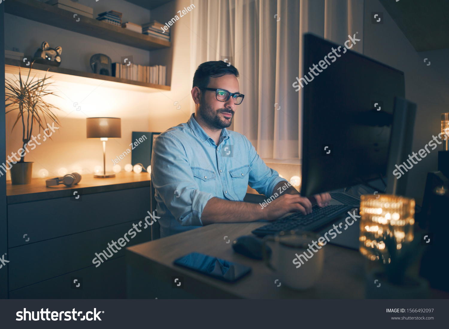 Modern young man working remotely from home at night.  #1566492097
