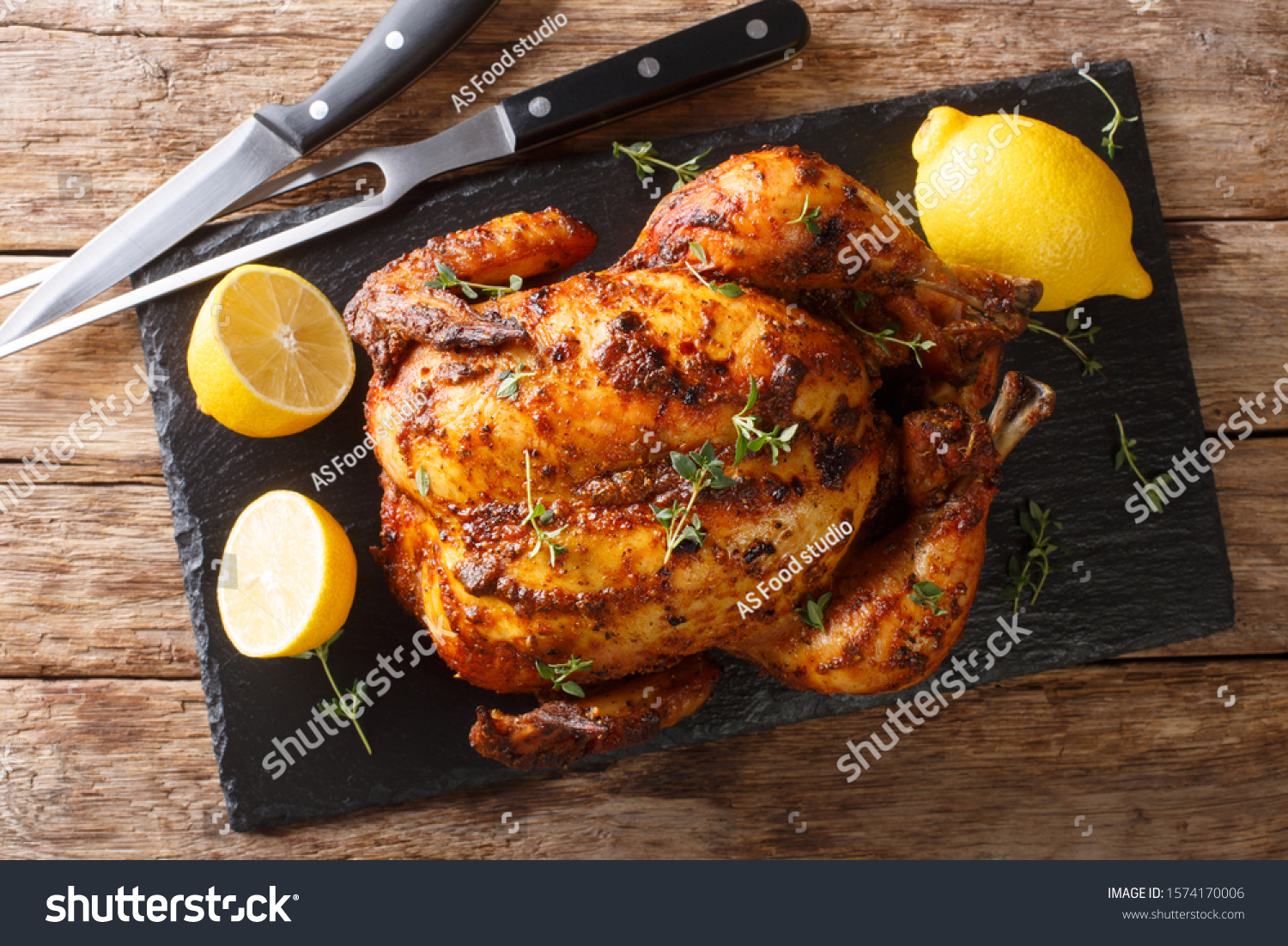 Homemade chicken rotisserie with thyme, lemon closeup on a slate board on the table. Horizontal top view from above #1574170006