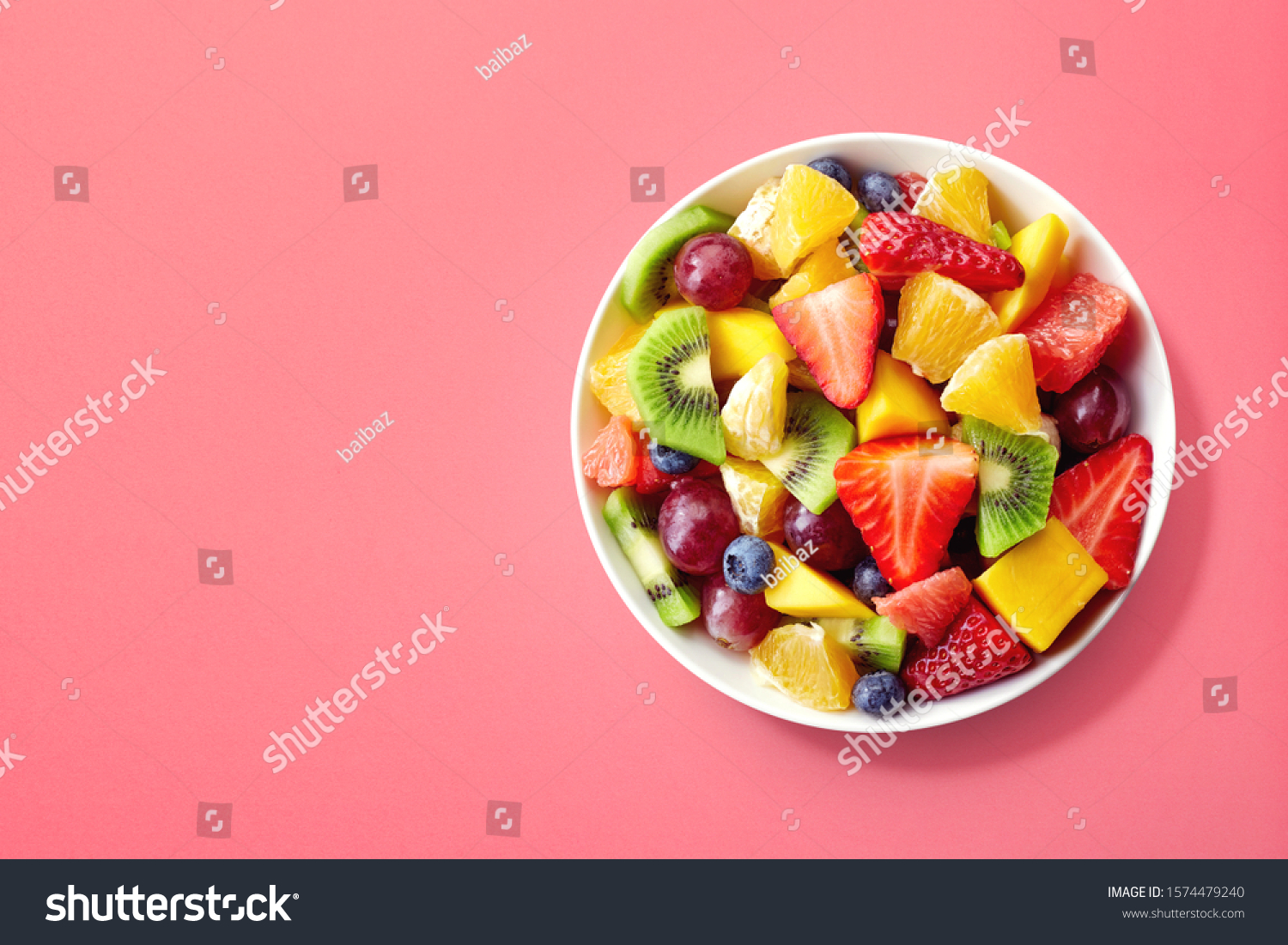 Bowl of healthy fresh fruit salad on pink background, top view #1574479240