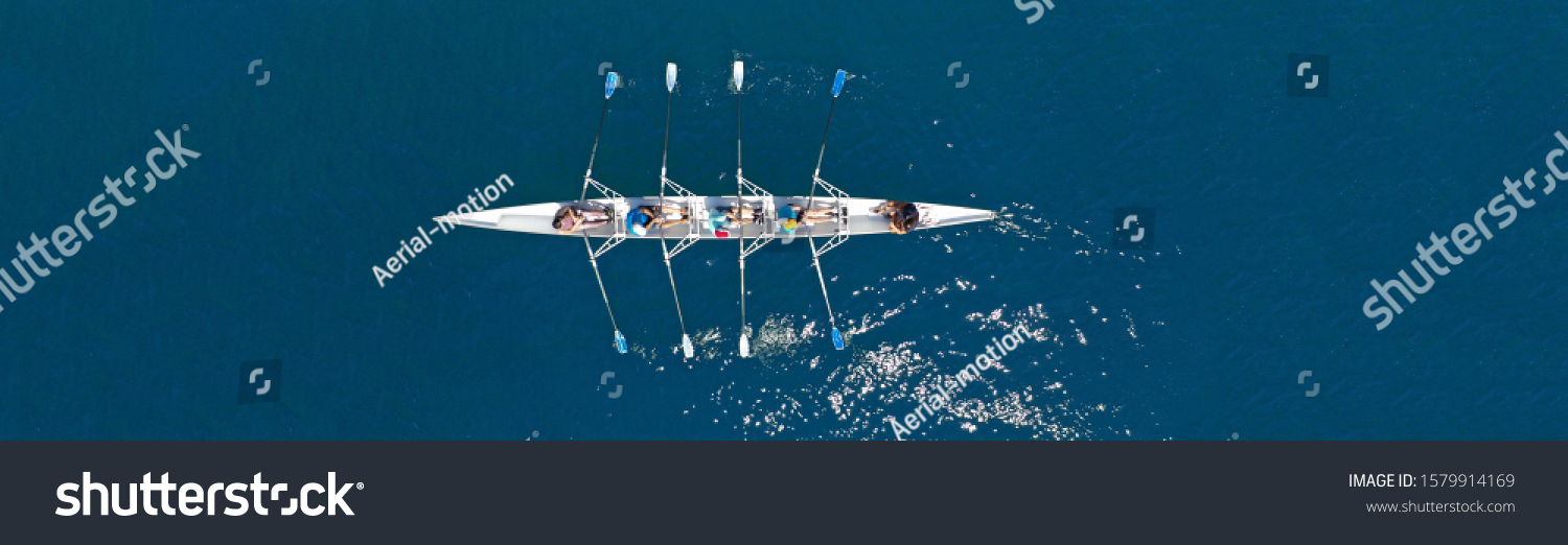 Aerial drone top ultra wide panoramic view of sport canoe rowing synchronous team of athletes competing in deep blue sea #1579914169